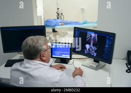 Männlicher Diagnostiker führt mit modernen Geräten einen CT-Scan durch Stockfoto