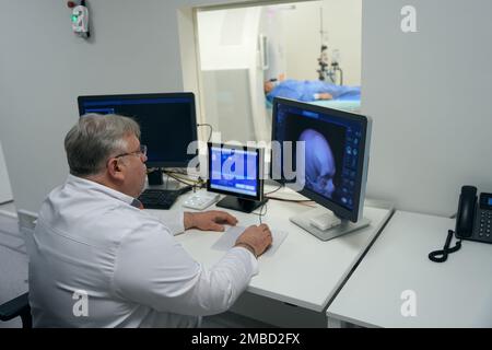 Erfahrener Arzt sitzt vor Monitoren von Diagnosegeräten Stockfoto