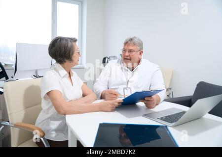 Ältere Frau kommuniziert mit einem Arzt in seiner Praxis Stockfoto