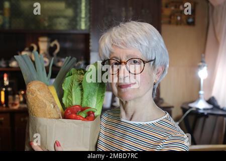 Seniorin, die Papiertüte mit Lebensmitteln in der Hand hält Stockfoto