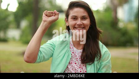 Starke junge Frau, die die Faust in die Luft erhebt und zur Kamera lächelt Stockfoto