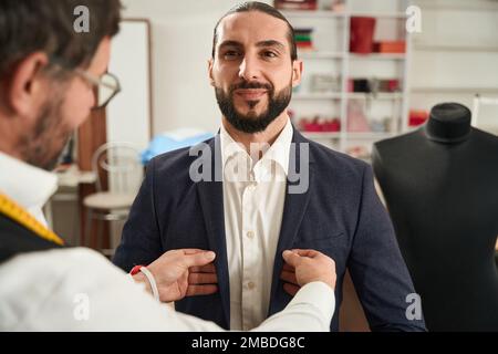 Erfahrener Couturier, der jungen Mann anprobiert Stockfoto