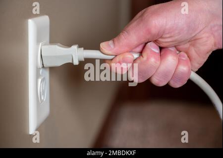 Falsche Methode zum Ziehen des Netzkabels aus der Steckdose demonstrieren Stockfoto