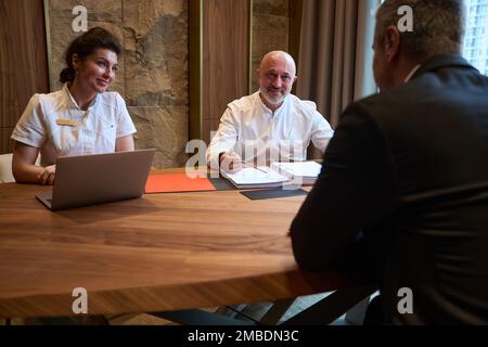 Freundliche Ärzte und ein Kunde sitzen an der Rezeption Stockfoto