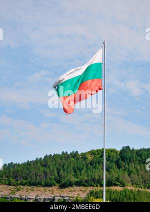 Die bulgarische Nationalflagge winkt im Wind gegen den blauen Himmel. Stockfoto