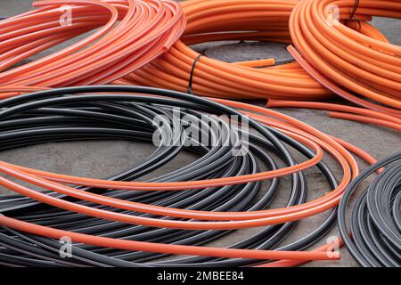 Installationen und Entwicklung von Communications, große Spiralrollen aus PVC-Rohrrohr-Kunststoff. Schläuche auf der Baustelle, Schutz der Elektrokabel und Stockfoto