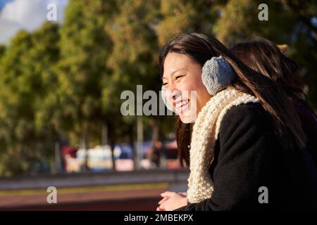 Junge Frau, die sich auf eine Brücke lehnt, wegschaut, die Aussicht genießt und lächelt. Stockfoto