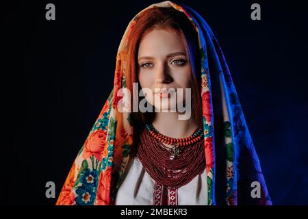 Bezaubernde Ingwer in traditionellem ukrainischem Taschentuch, Halskette und gestickter Bluse auf schwarzem Hintergrund. Ukraine, Stil, Volk, ethnische Kultur Stockfoto