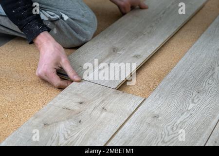 Ein Mann legt einen Laminatboden. Reparatur in der Wohnung. Laminatboden professionell montiert Stockfoto
