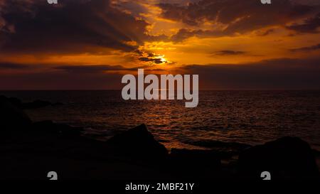 Ein malerischer, lebhafter Sonnenuntergang vor der felsigen Küste Stockfoto