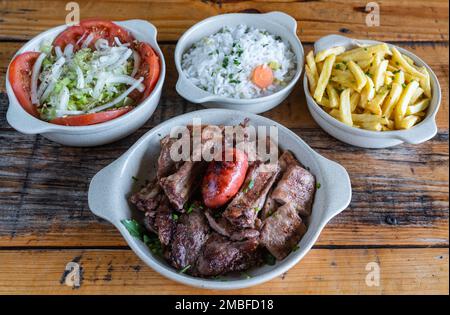 Gemischtes Fleisch, gegrillt auf einem Teller mit Gemüsesalat, Reiskartoffeln, Cusida. Mediterrane traditionelle Speisen Stockfoto