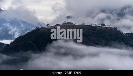 Die Ruinen der Burg Takeda in Asago, Präfektur Hyogo, Japan, mit Wolken, die über den Hügel fließen. Stockfoto