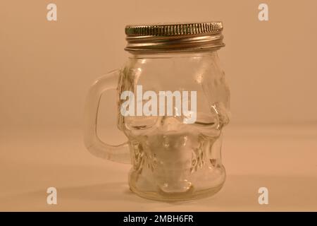 Ein Glas Salz in Form eines Schädeltreffers auf weißem Hintergrund Stockfoto