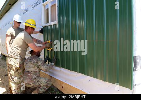 Army Reserve Staff Sgt. Ethan Cowell, steht mit Bohrer, Leiter des Baukommandos, 389. Engineer Company, verschraubt Metallverkleidung als Teil eines Bauprojekts in Fort McCoy, Wisconsin, 16. Juni 2022. Cowell und andere Ingenieure der 389. en. Co. Führt hier jährliche Schulungen durch und arbeitet während dieser Zeit an der Verbesserung der Schulungsbereiche. Stockfoto