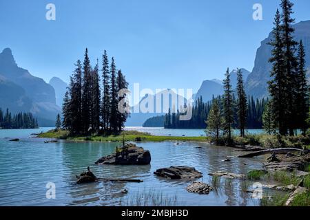 Spirit Island und das Ufer mit den weit entfernten Gipfeln der Kanadischen Rockies und dem leicht gewundenen Wasser des Maligne Lake bei Jasper, Alberta. Stockfoto