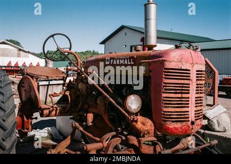 Auf der Spring Brook Farm in Littleton, Massachusetts, steht ein alter roter Farmall-Traktor vor blauem Himmel. Bild wurde auf analogem Farbfilm aufgenommen. Stockfoto