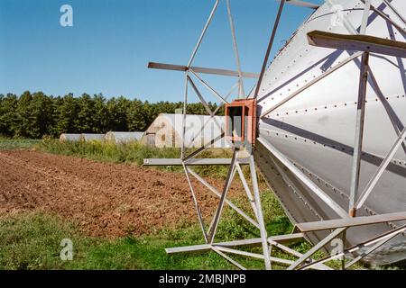 Auf der Spring Brook Farm in Littleton, Massachusetts, befindet sich ein umgestürztes Silo vor einer Reihe von Gewächshäusern. Bild wurde in analoger Farbe aufgenommen Stockfoto