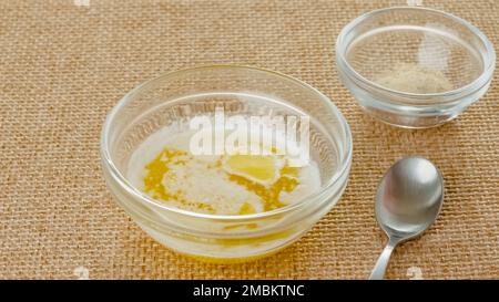 Geschmolzene Butter in einer Glasschüssel und Knoblauchgewürze in einer Glasschüssel, Nahaufnahme auf einem Küchentisch Stockfoto
