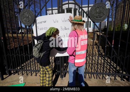 Derenda Hancock, co-director of the Jackson Women's Health Organization clinic patient escorts, better known as the Pink House defenders, right, and escort Heidi Barnett, adjust a signed sign calling for abortion rights on the front gate of the Mississippi Governor's Mansion in Jackson, Friday, Jan. 20, 2023. A small group of abortion rights advocates demonstrated at the building's gates, countering the national March For Life gatherings, while carrying signs calling for abortion rights. A state law banning most abortions, went into effect July 7, 2022. (AP Photo/Rogelio V. Solis)