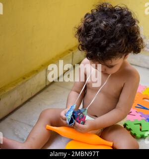 Süßer kleiner Junge Shivaay Sapra auf dem Balkon zu Hause im Sommer, süßer kleiner Junge Fotoshooting bei Tageslicht, kleiner Junge genießt zu Hause während Pho Stockfoto