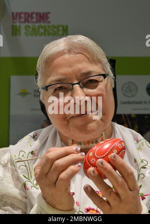 Berlin, Deutschland. 20. Januar 2023. Helene Herberg von der Vereinigung "Landurlaub in Sachsen" färbt während der Internationalen Grünen Woche (IGW) am Stand in der Ausstellungshalle Sachsen ein Ei mit einer Feder und rotem Wachs. Die weltweit größte Messe für Lebensmittel, Landwirtschaft und Gartenbau existiert seit 1926, und seit 1996 findet auch die Messe Heim-Tier & Pflanze im Rahmen der Messe statt. Die diesjährige Ausgabe endet am 29.01.2023. Kredit: Soeren Stache/dpa/Alamy Live News Stockfoto