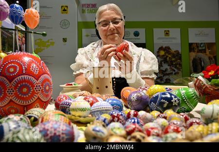 Berlin, Deutschland. 20. Januar 2023. Helene Herberg von der Vereinigung "Landurlaub in Sachsen" färbt während der Internationalen Grünen Woche (IGW) am Stand in der Ausstellungshalle Sachsen ein Ei mit einer Feder und rotem Wachs. Die weltweit größte Messe für Lebensmittel, Landwirtschaft und Gartenbau existiert seit 1926, und seit 1996 findet auch die Messe Heim-Tier & Pflanze im Rahmen der Messe statt. Die diesjährige Ausgabe endet am 29.01.2023. Kredit: Soeren Stache/dpa/Alamy Live News Stockfoto