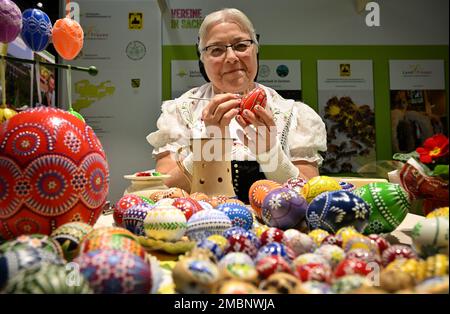 Berlin, Deutschland. 20. Januar 2023. Helene Herberg von der Vereinigung "Landurlaub in Sachsen" färbt während der Internationalen Grünen Woche (IGW) am Stand in der Ausstellungshalle Sachsen ein Ei mit einer Feder und rotem Wachs. Die weltweit größte Messe für Lebensmittel, Landwirtschaft und Gartenbau existiert seit 1926, und seit 1996 findet auch die Messe Heim-Tier & Pflanze im Rahmen der Messe statt. Die diesjährige Ausgabe endet am 29.01.2023. Kredit: Soeren Stache/dpa/Alamy Live News Stockfoto