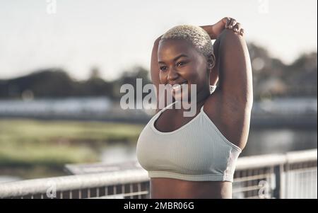 Beim Training fühle ich mich gut. Eine attraktive junge Frau, die sich draußen ausstreckt. Stockfoto