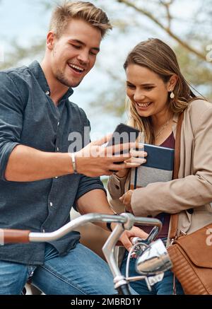 Eine gute Diskussion ist wie Reichtum. Zwei junge Schüler, die ein Mobiltelefon draußen auf dem Campus benutzen. Stockfoto