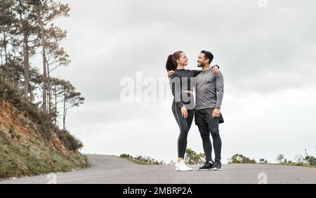 Ein guter Sportkamerad ist alles, was du brauchst. Aufnahme von zwei jungen Athleten in voller Länge, die nach ihrem morgendlichen Lauf im Freien mit den Armen umeinander stehen Stockfoto