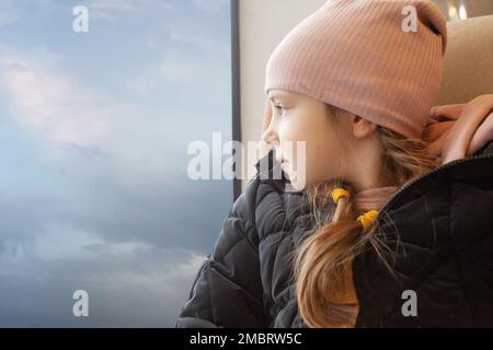 Süßes kleines Mädchen, das auf einer Reise durch das Fenster starrt Stockfoto