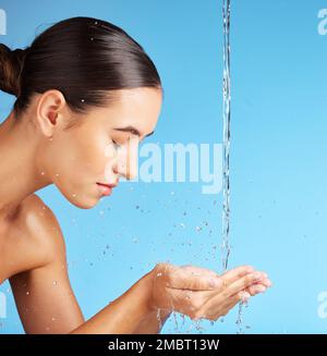 Frau, Hände und Wasser für Gesichtswäsche, Hautpflege, Hydratation oder Hygiene vor blauem Hintergrund. Schönes weibliches Modell in der Gesichtsreinigung, -Reinigung oder Stockfoto