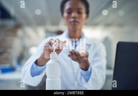 Die Krankheit hört heute auf. Eine Wissenschaftlerin desinfiziert ihre Hände, während sie in einem Labor forscht. Stockfoto