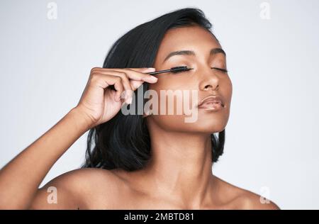 Dreh die Lautstärke deiner Wimpern auf. Eine schöne junge Frau, die Mascara aufträgt. Stockfoto