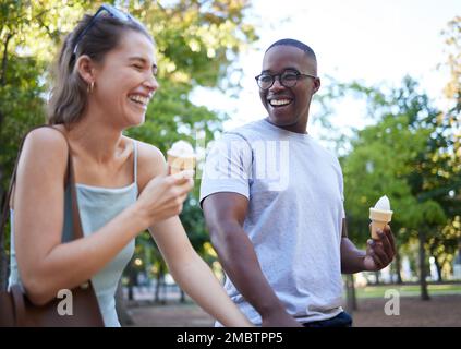 Gemischtrassiges Paar, Lachen und Eis für lustige Witze, Unterhaltung oder eine Beziehung im Park. Glücklicher Mann und glückliche Frau, die lachen und lächeln Stockfoto