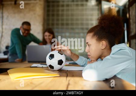 Eine nachdenkliche Frau, die an einem Tisch sitzt, in einem Gemeinschaftsarbeitsplatz Stockfoto
