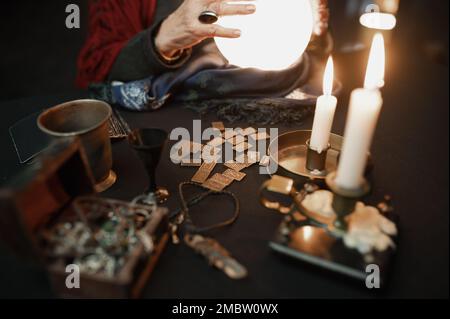 Wahrsager, die Kristallkugel benutzen, um die Zukunft am Tisch in der Dunkelheit vorherzusagen Stockfoto