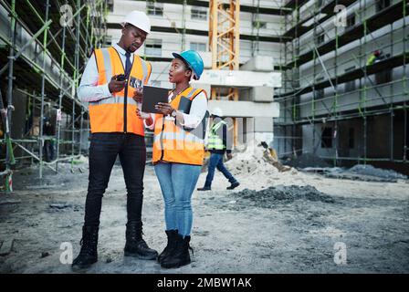 Der Immobilienmarkt wird gleich etwas größer. Ein junger Mann und eine junge Frau, die sich auf einer Baustelle unterhalten. Stockfoto