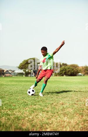 Der beste Start in den Tag. Ein kleiner Junge, der Fußball auf einem Sportplatz spielt. Stockfoto