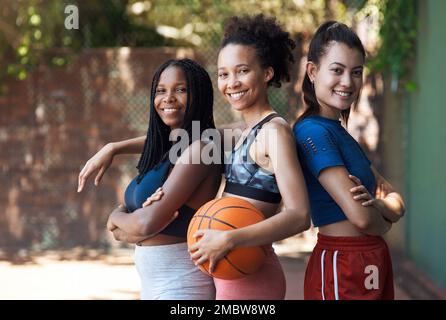 Wir sind bereit. Du bist es. Verkürztes Porträt von drei attraktiven jungen Sportlerinnen, die auf dem Basketballplatz zusammenstehen. Stockfoto