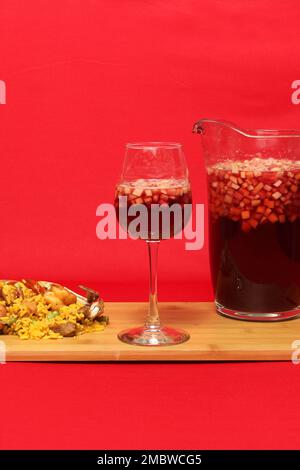 Paella-Reis mit Meeresfrüchten, traditionelles Gericht aus Valencia Spanien, serviert auf einem weißen Teller neben einem Krug mit Büroangestellten mit Früchten und einem Kristallglas Stockfoto