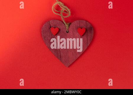 Valentinstag-rotes Herz aus Holz auf rotem Hintergrund mit kleinen Herzen Stockfoto