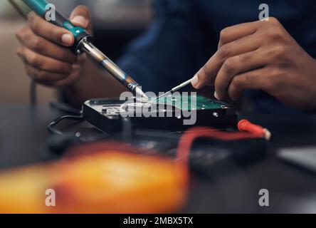 Kommen wir zum zugrunde liegenden Problem. Ein Techniker, der einen Lötkolben verwendet, um Computerhardware zu reparieren. Stockfoto