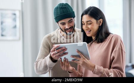 Ein intelligentes Gerät für ein intelligentes Paar. Ein junger Mann und eine junge Frau, die von zu Hause aus mit einem digitalen Tablet arbeiten. Stockfoto