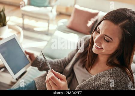 Tablet, Kreditkarte und Frau auf dem Sofa, die im Wohnzimmer online einkauft. FinTech, E-Commerce und eine glückliche Frau mit dem Kauf von Technologie Stockfoto