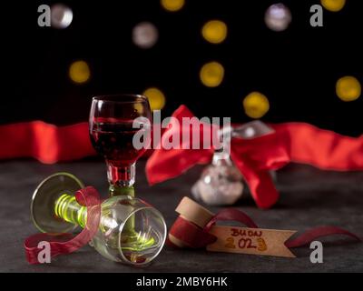 Zwei Gläser Rotwein, eines davon verkehrt herum, und ein Zettel mit der Aufschrift Buon 2023, was auf Italienisch bedeutet glücklich 2023 Stockfoto