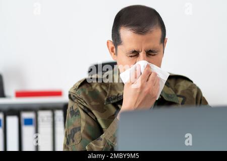 Aufnahme eines erwachsenen Soldaten, der sich bei der Arbeit mit einem Taschentuch die Nase bläst Stockfoto