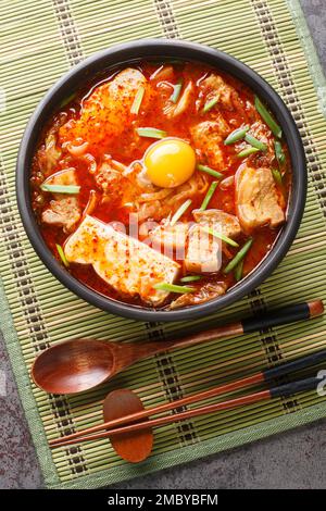 Sundubu Jjigae scharfe Kimchi Soft Tofu Eintopf-Nahaufnahme auf der Schüssel auf dem Tisch. Vertikale Draufsicht von oben Stockfoto