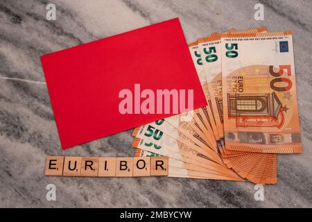 Word EURIBOR ist in Holzbuchstaben geschrieben, in der Nähe von 50 Euro-Banknoten und rotem Umschlag. Stockfoto