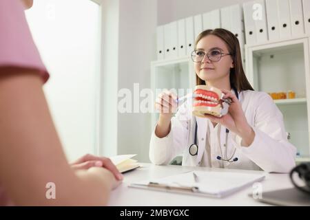 Arzt, der dem Patienten zeigt, wie er seine Zähne richtig putzen kann, am Modell des menschlichen Kiefers in der Klinik Stockfoto